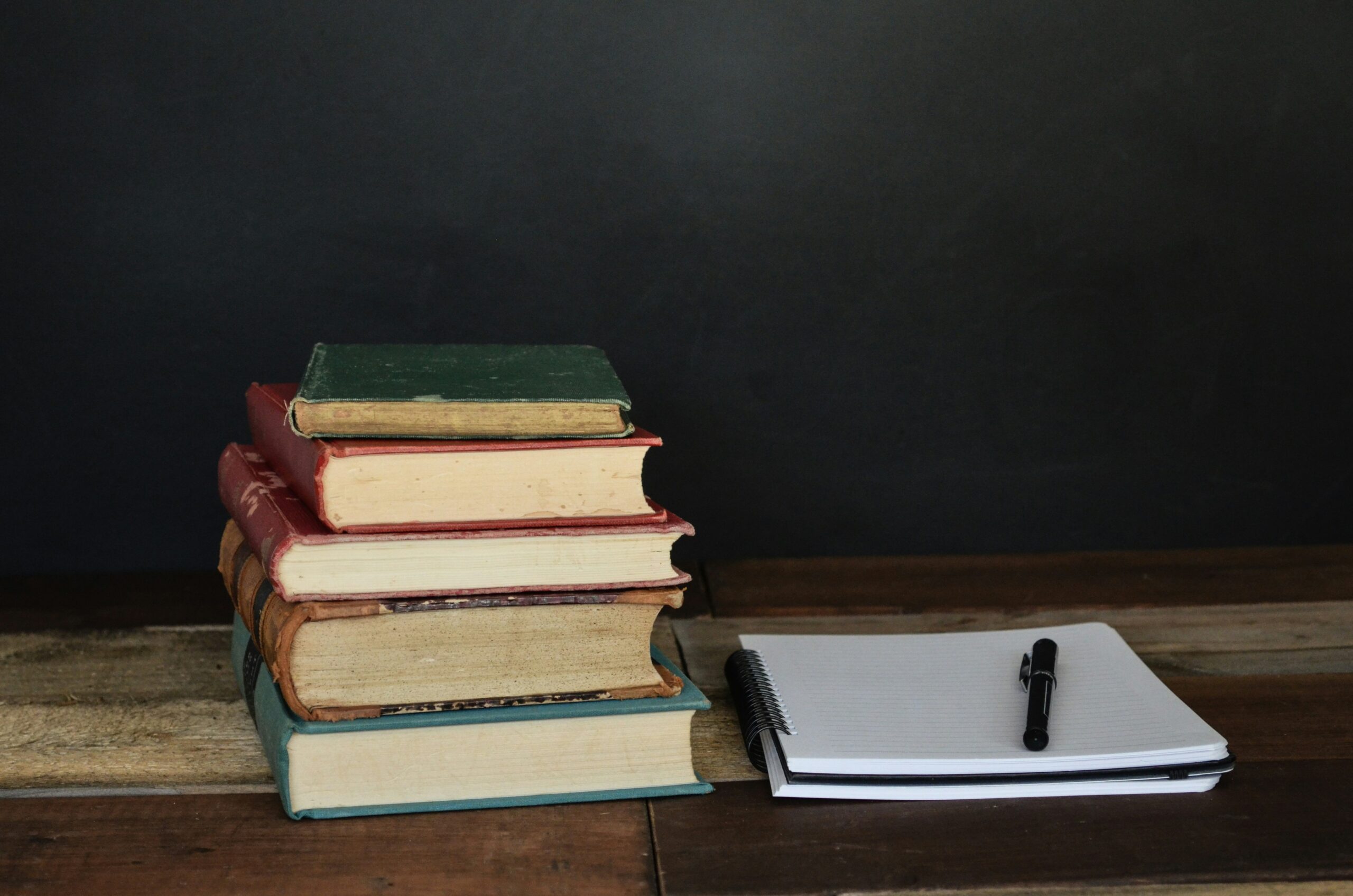Stack of academic books with notebook and pen representing musicology and academic text translation